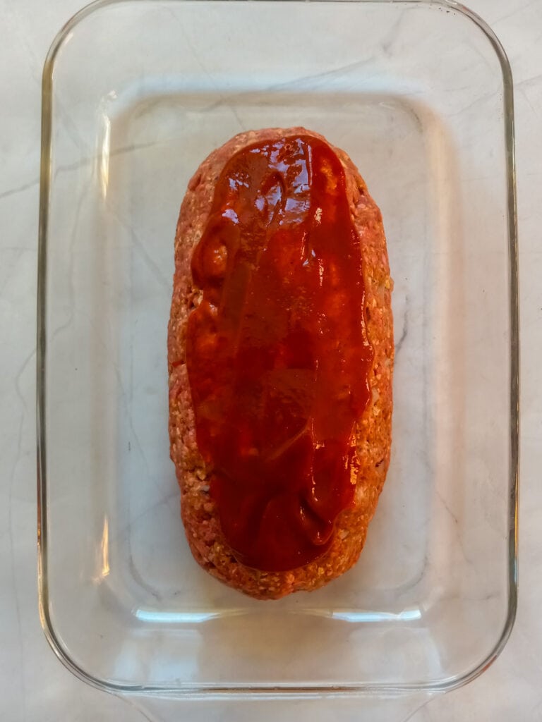 meatloaf in a pan with glaze on top.