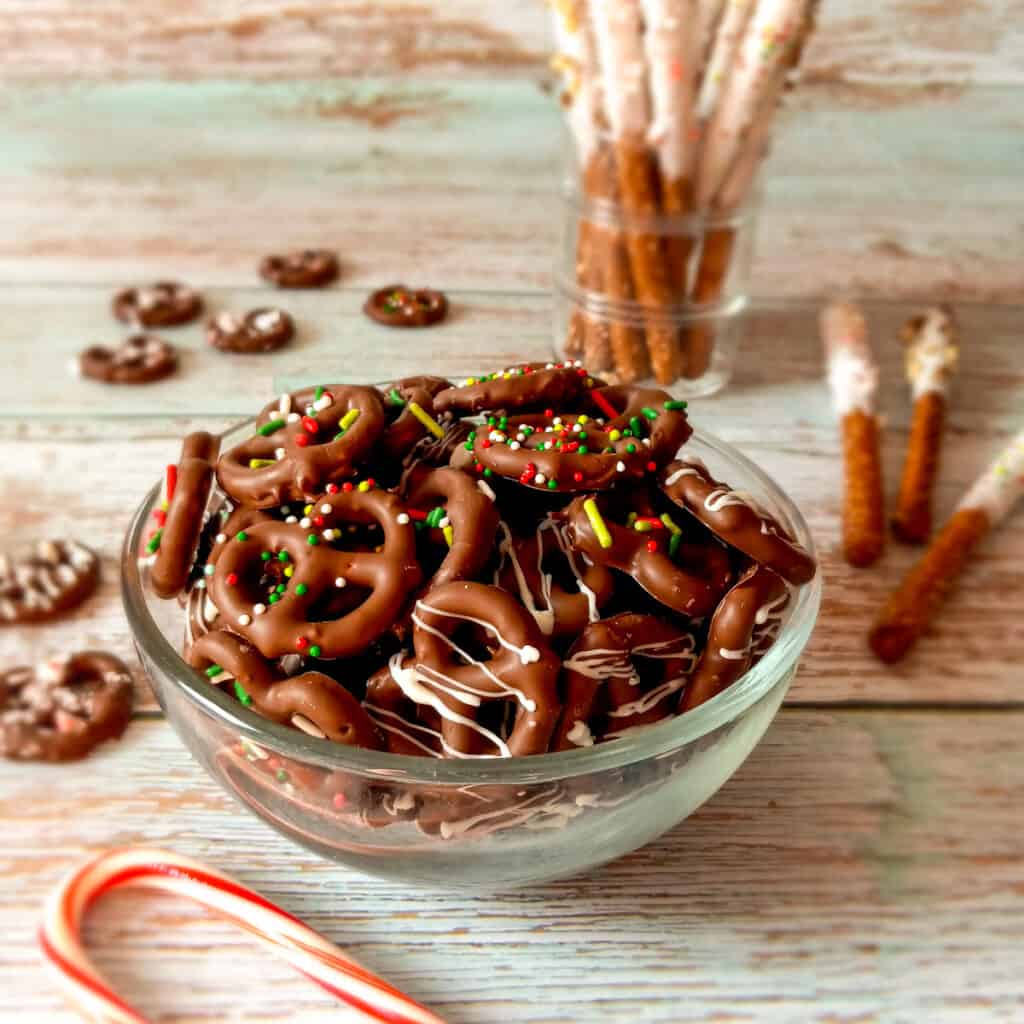 a bowl of chocolate coated pretzel twists and a cup of coated pretzel rods.