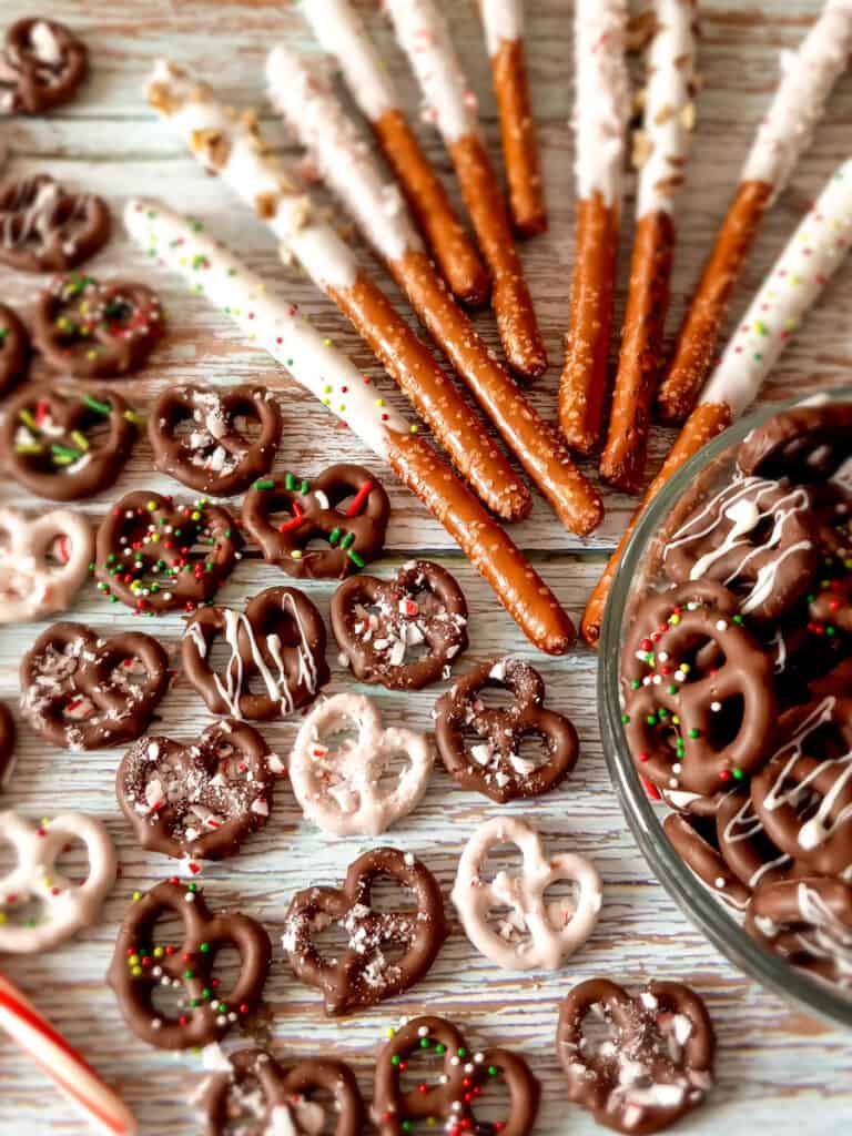 chocolate coated almond bark pretzel minis and rods spread around on a bluish backdrop.