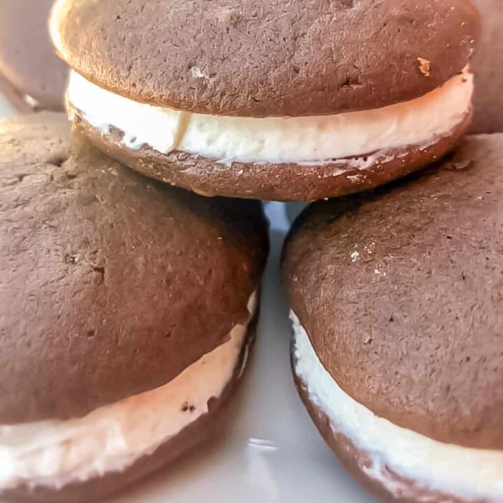 A stack of chocolate whoopie pies with frosting.
