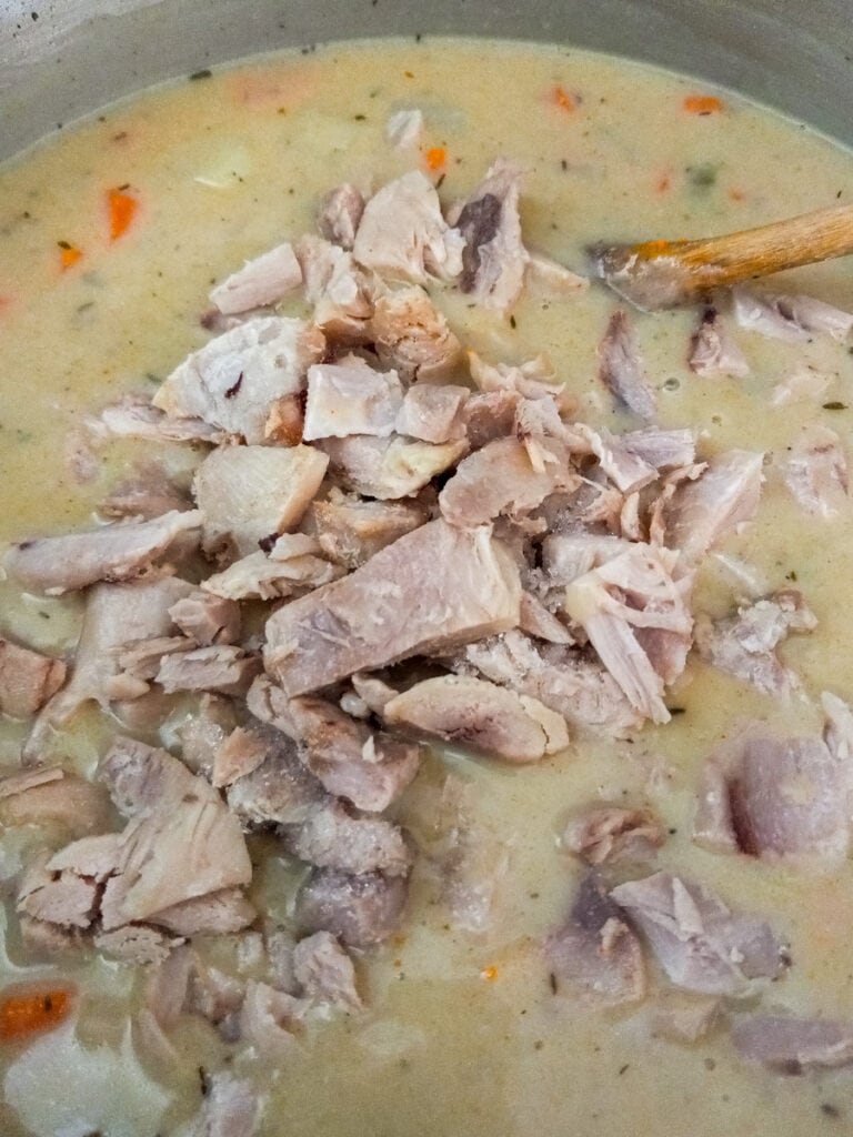 adding cooked and chopped chicken to the pot.