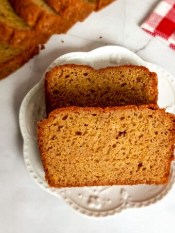 Amish friendship bread slices on a plate and more slices in the background.