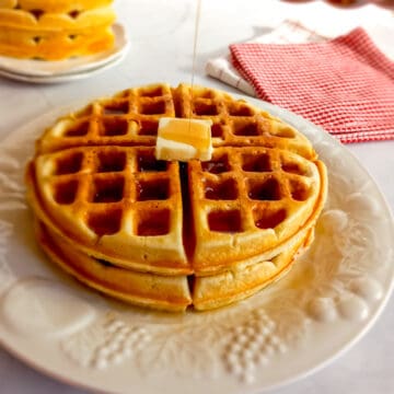 drizzling syrup over homemade waffles on a plate.
