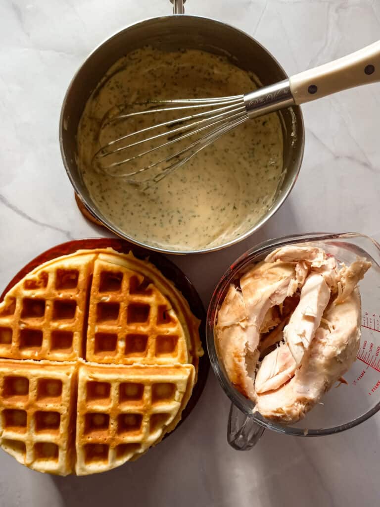 chicken picked off the bone, a pot of gravy, and a stack of waffles.
