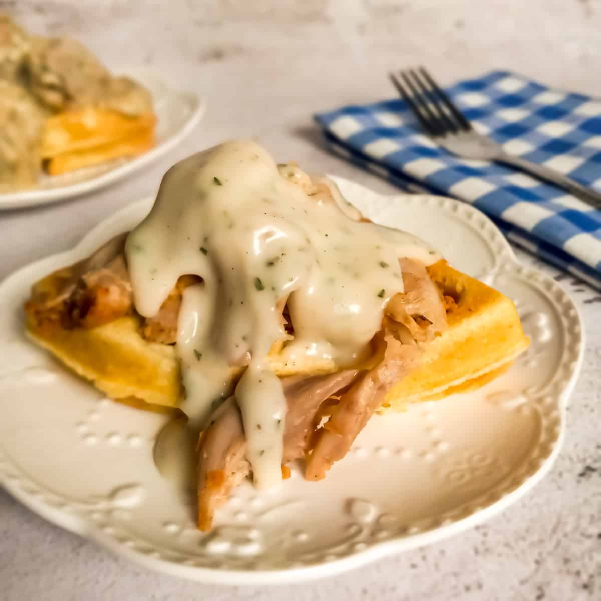 PA Dutch waffle on a plate topped with chicken and gravy.