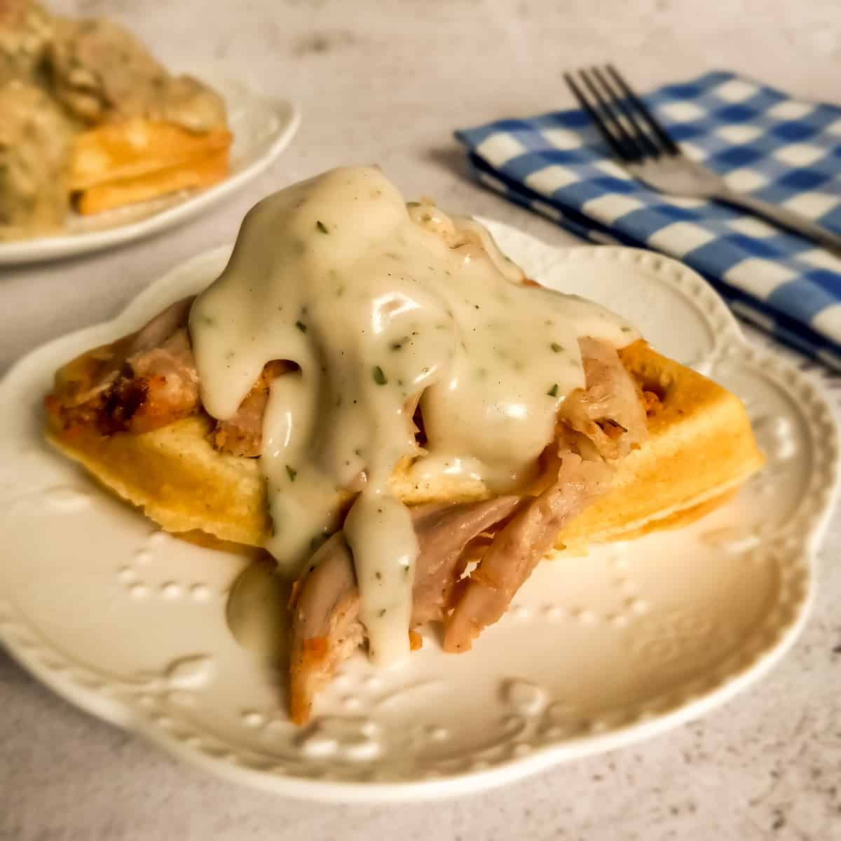 a homemade waffle on a plate topped with chicken and white gravy - dirt cheap meal.
