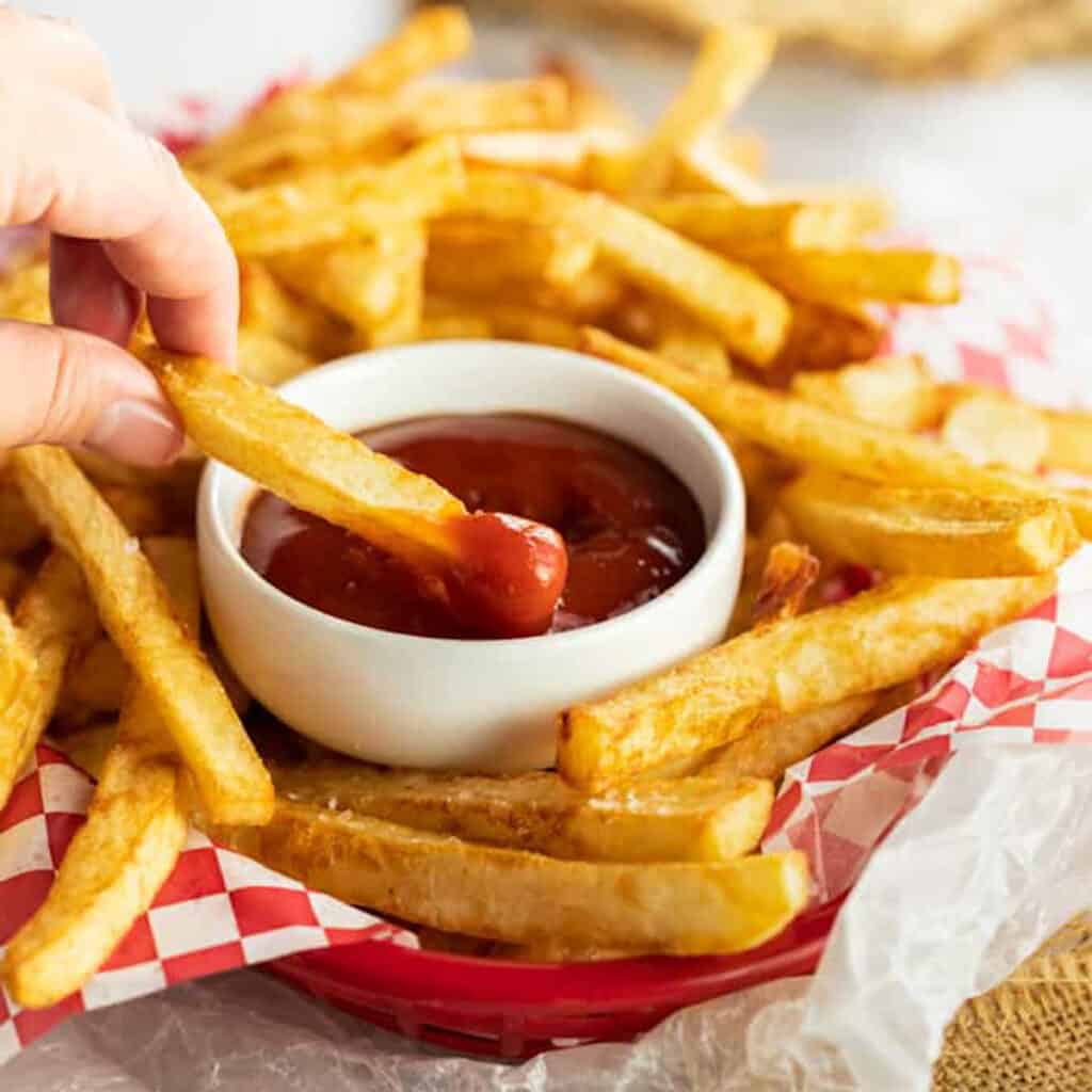 a plate of french fries with a small bowl of ketchup.