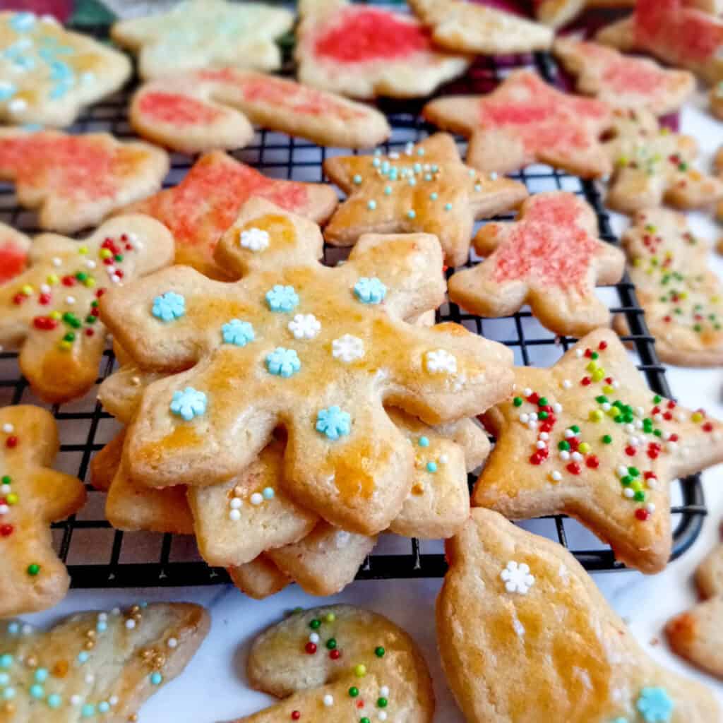 sand tart cutout cookies decorated with sprinkles on a wire rack.