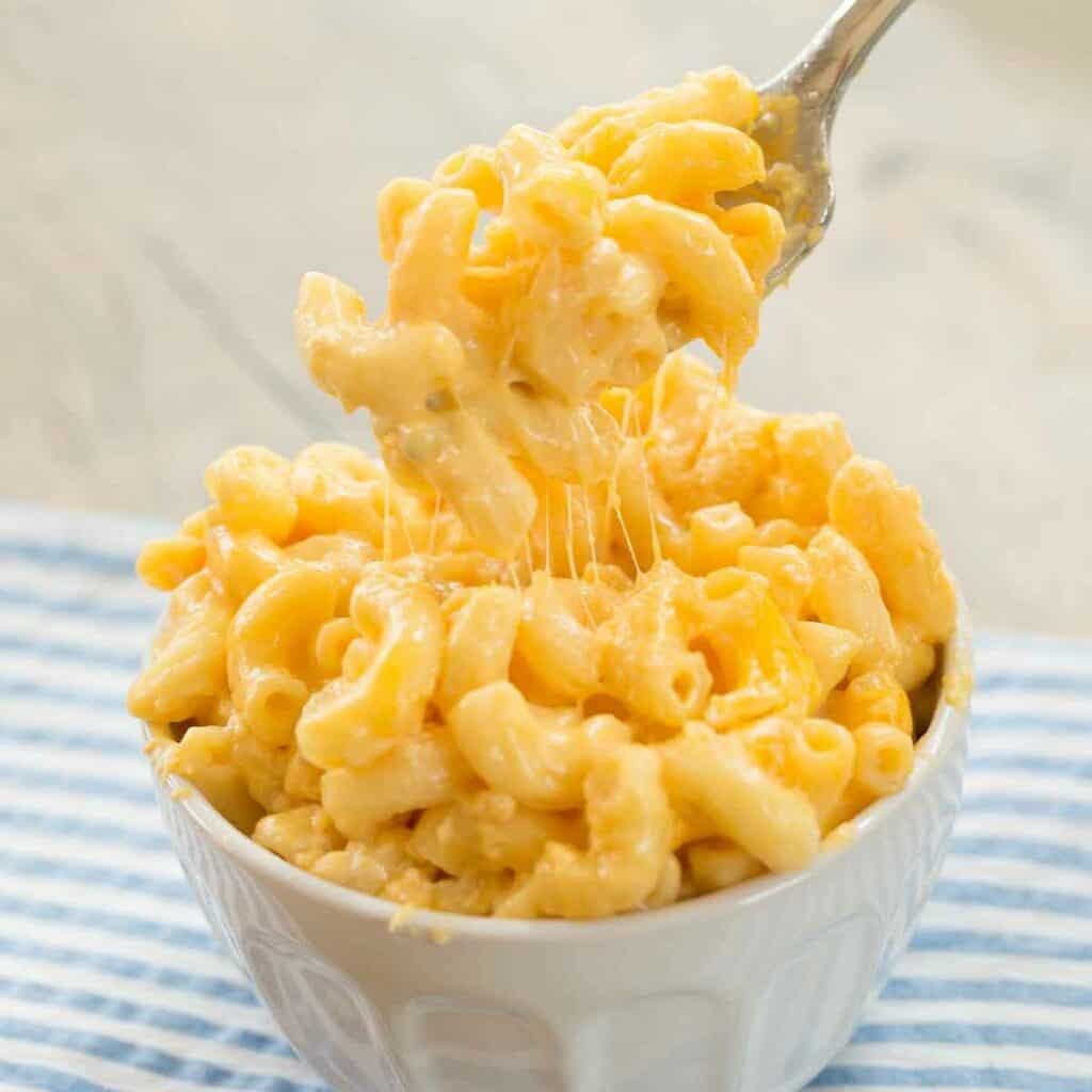 a fork digging into a dish piled high with mac and cheese.