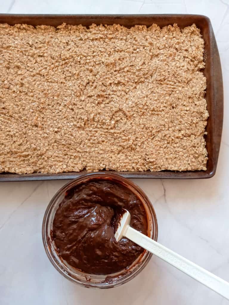 part of the oat mixture spread into a 10x15" pan with the chocolate fudge in a separate bowl.