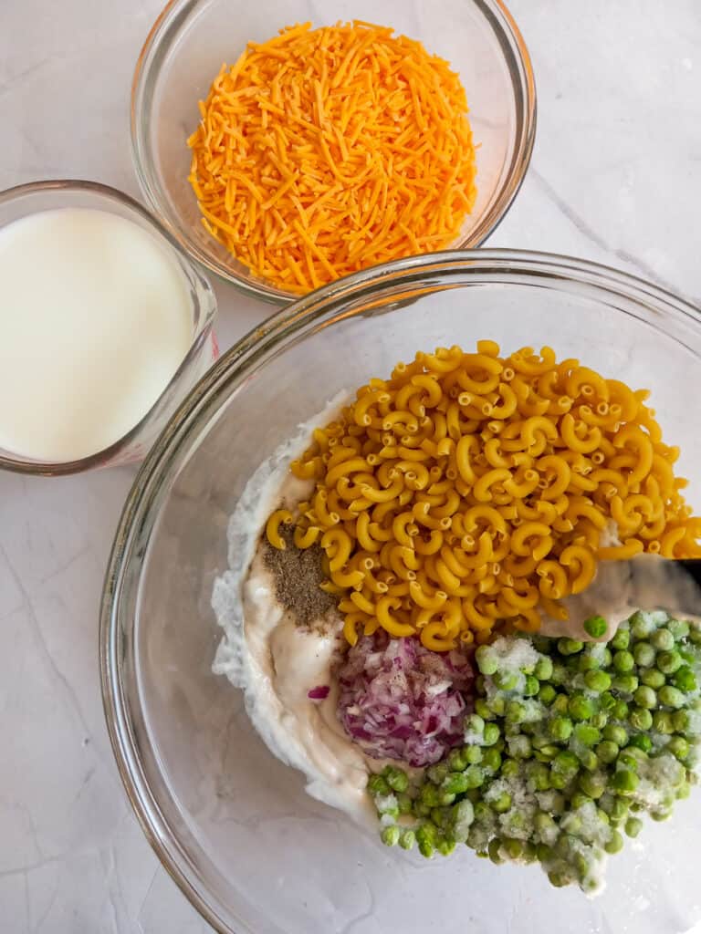 mixing ingredients in a large bowl, cheese, and milk in separate dishes.