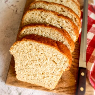 Amish oatmeal bread loaf sliced on a board.