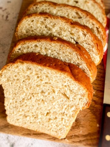 Amish oatmeal bread loaf sliced on a board.