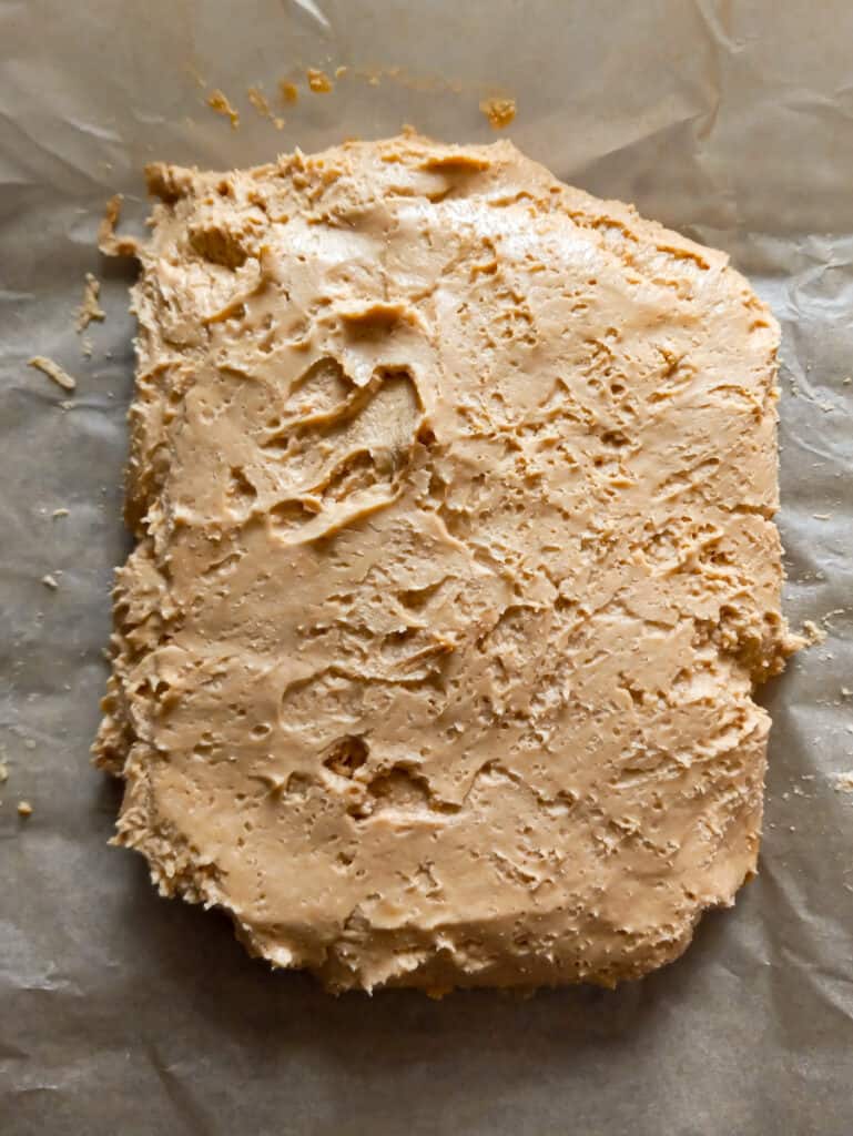 peanut butter mixture spread onto parchment paper to refrigerate.