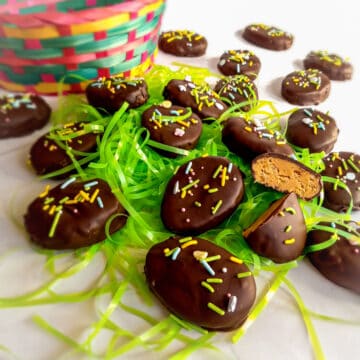 chocolate peanut butter eggs scattered around with an Easter basket and grass.