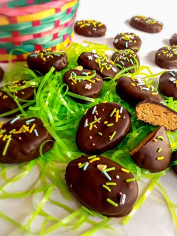 chocolate peanut butter eggs scattered around with an Easter basket and grass.