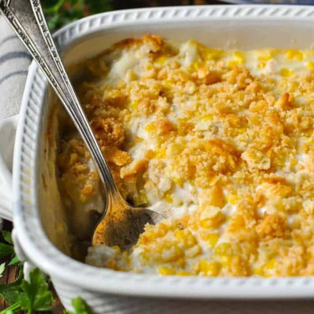 a white casserole dish with chicken and corn topped with crumbs.