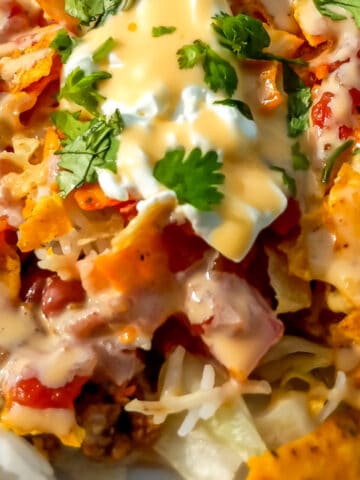 a delicious-looking Amish haystack dinner on a plate topped with cheese sauce.