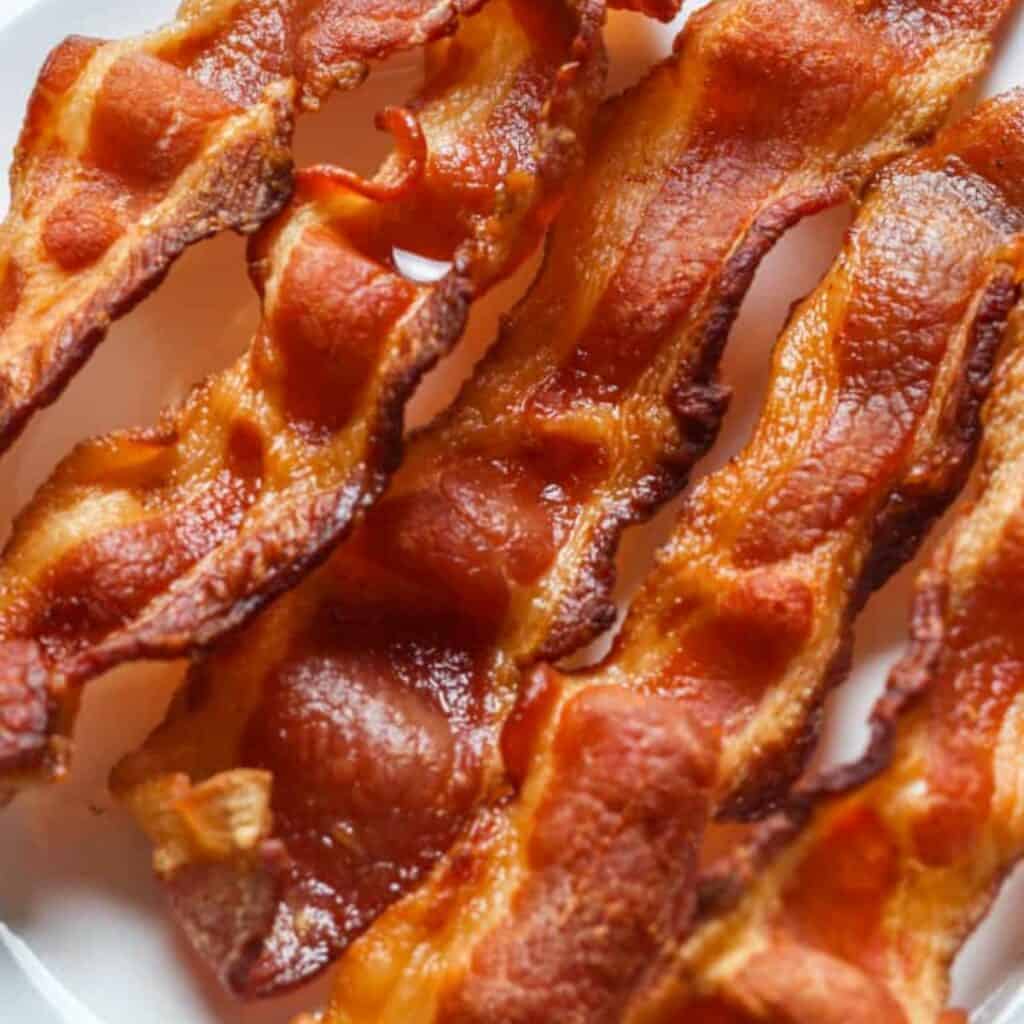 5 slices of crispy bacon a plate, perfect to serve with biscuits and gravy.