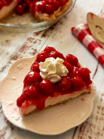 a slice of easy cherry pie on a plate and the remaining pie in the background.