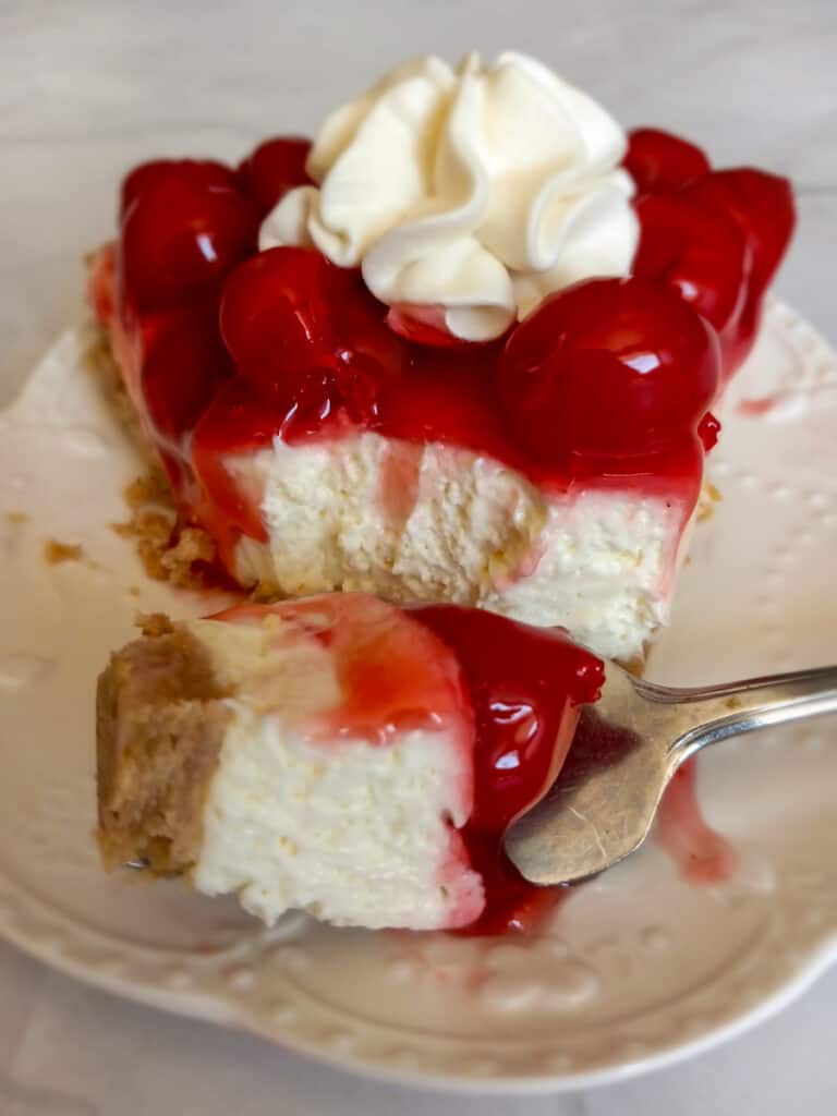 a slice of cherry cheesecake pie on a plate with a bite taken out of it.