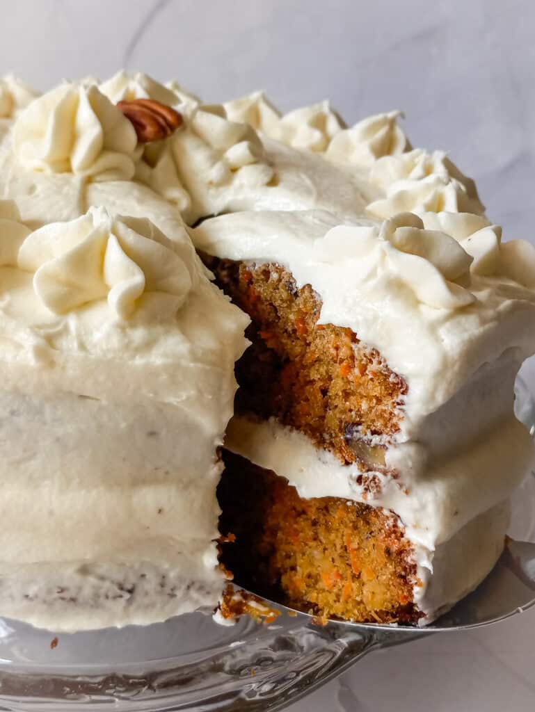 a slice of carrot cake cut out of the whole cake to show the inside.