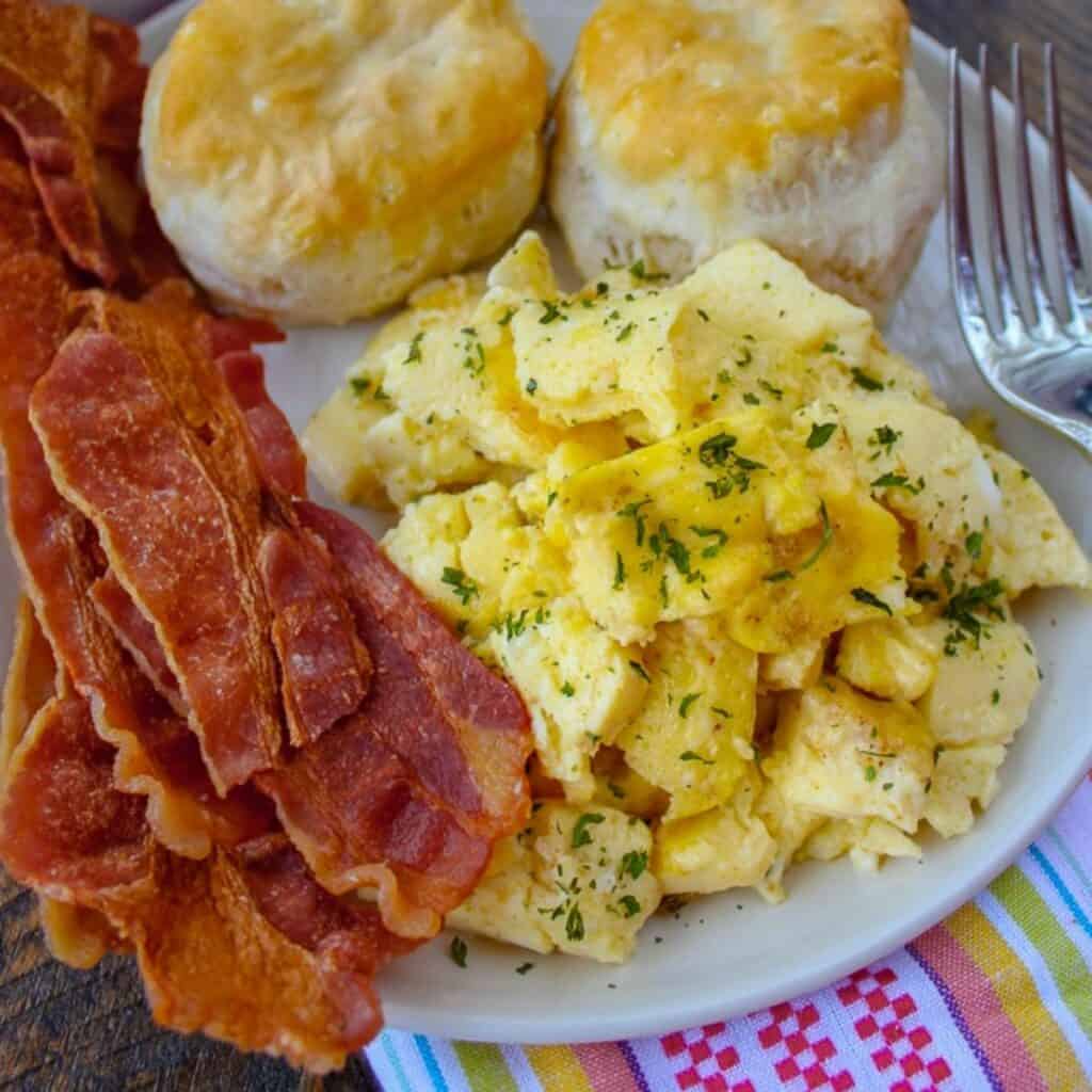 scrambled eggs, biscuits and bacon on a plate, perfect sides for sausage gravy.