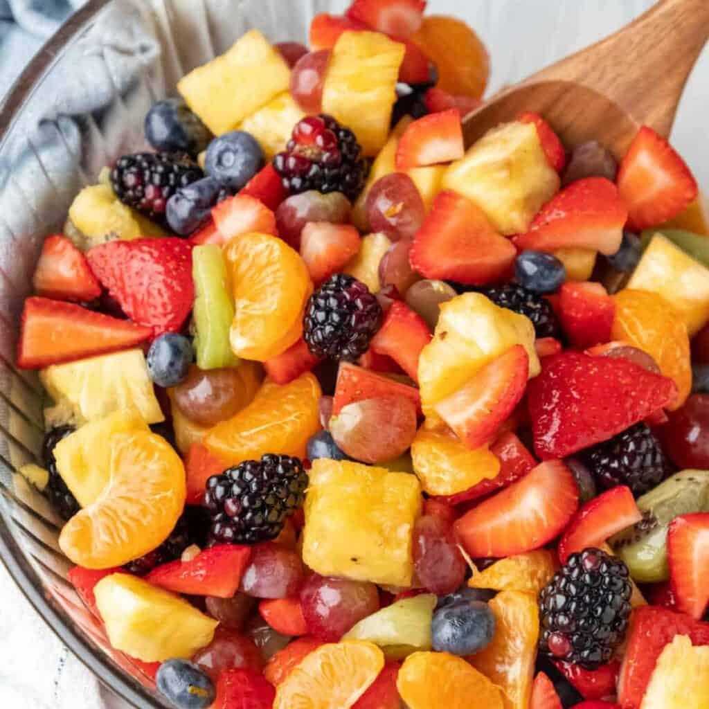 a bowl of delicious-looking fruit salad with lots of fresh fruit: berries, oranges, grapes, pineapple, etc..