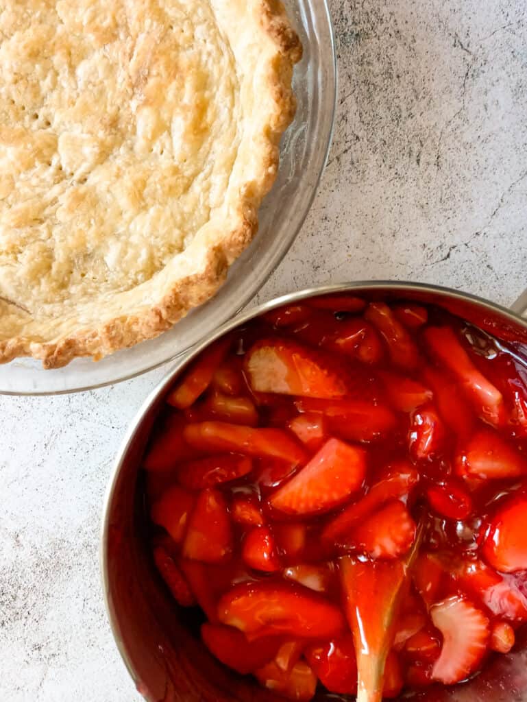 saucepan of strawberry pie filling and an empty prebaked pie crust.
