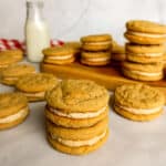 peanut butter whoopie pies stacked around a board with a jar of milk in the background.