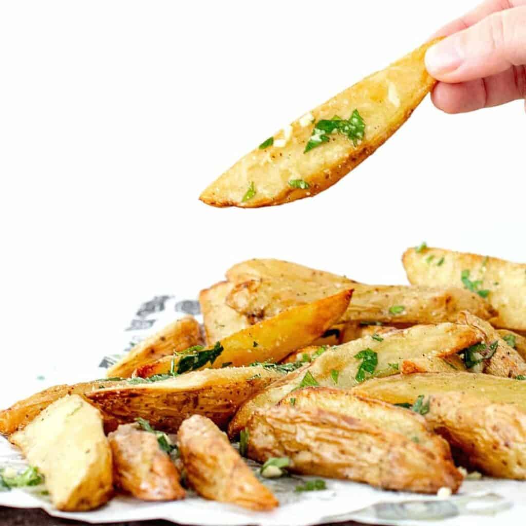stack of potato wedges and holding one wedge to display.