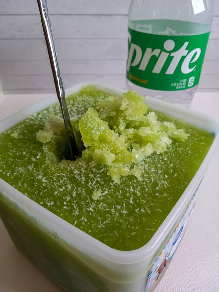 using a knife to chop a bucket of frozen slush.