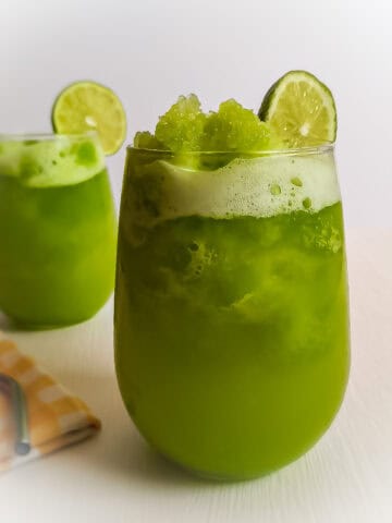 two glasses with a slice of lime on the rim, full of Amish lime slushies