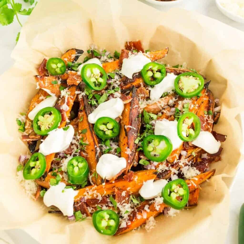 a dish of baked sweet potato fries loaded with sour cream, jalapenos, and cheese.