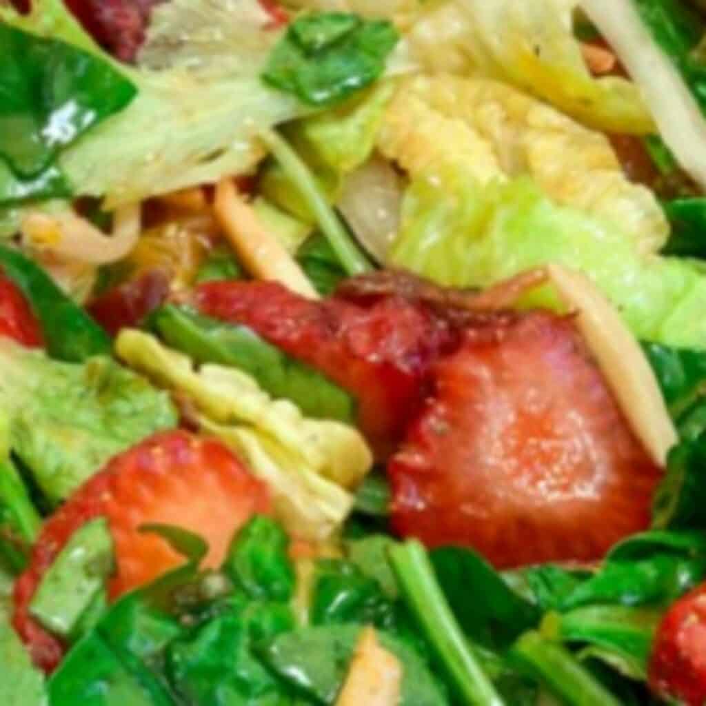 salad greens tossed with strawberry slices.