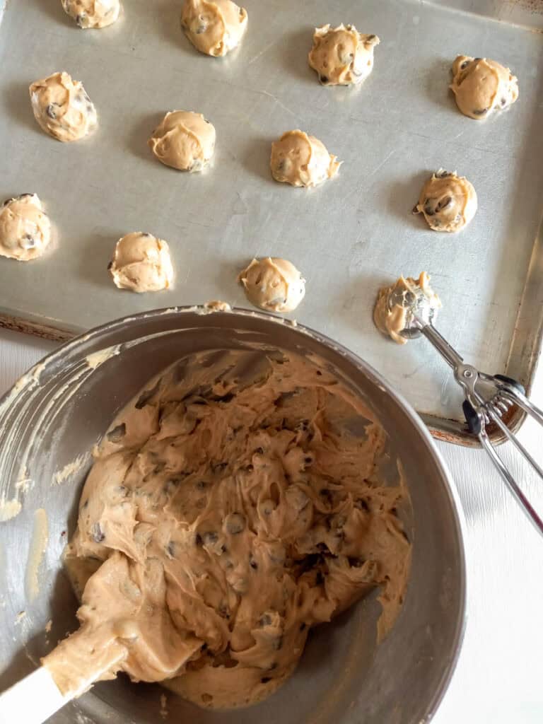 scooping batter onto a large cookie tray.