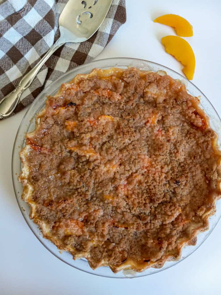 a whole baked peach crumb pie.