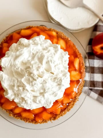 an Amish peach pie with graham crust and whipped cream on top.