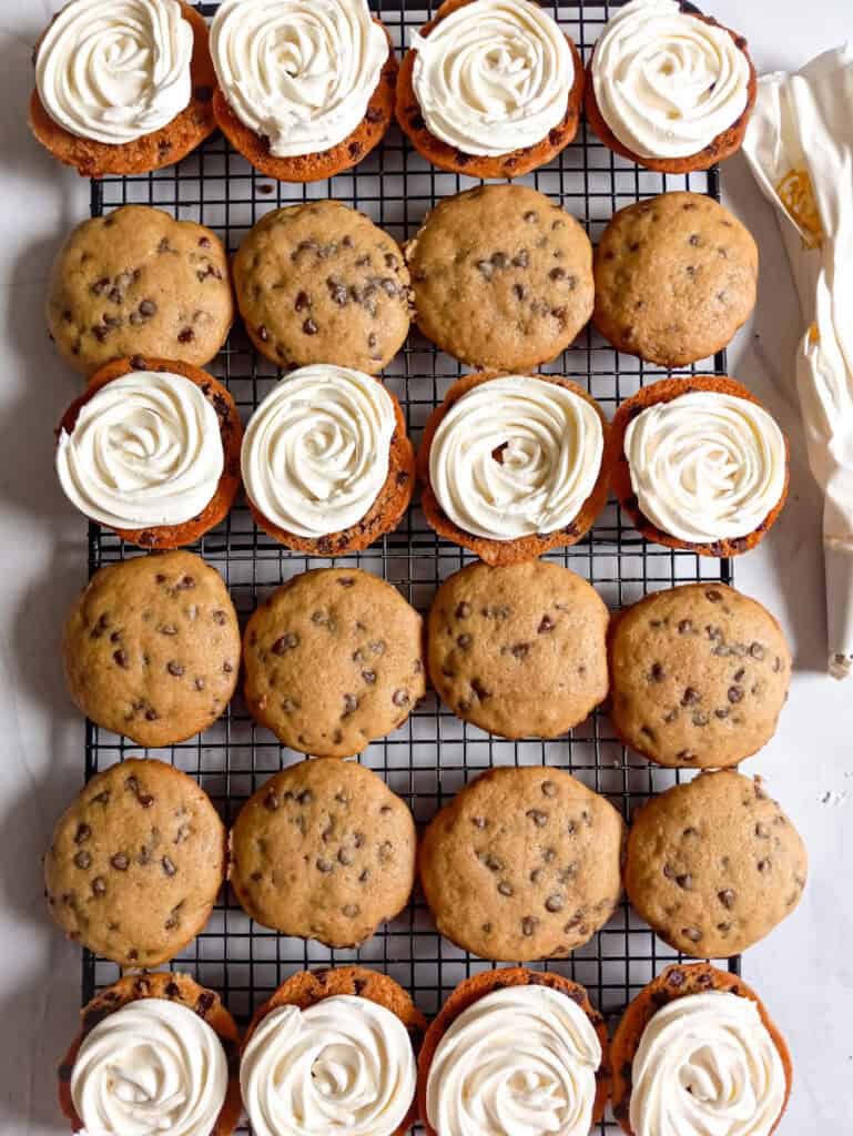 piping frosting onto the cookies on the wire rack.