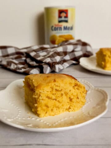 a slice of Amish cornbread on a plate with another one in the background.