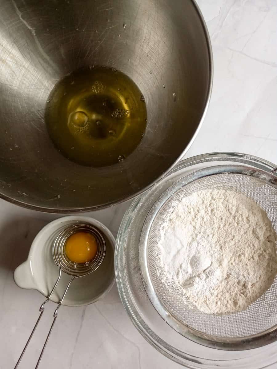 separating egg yolks from the whites, and another bowl with the dry ingredients ready to be sifted.