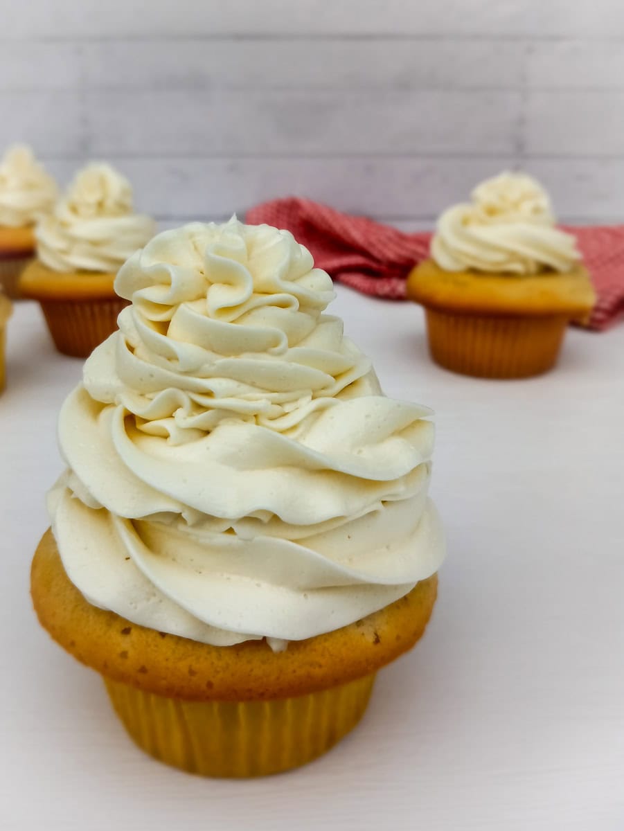 a white cupcake topped with a pile of buttercream.