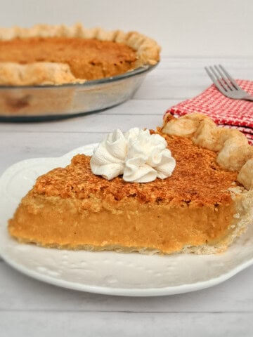 a slice of pumpkin pie with a dollop of whipped cream on a small plate.
