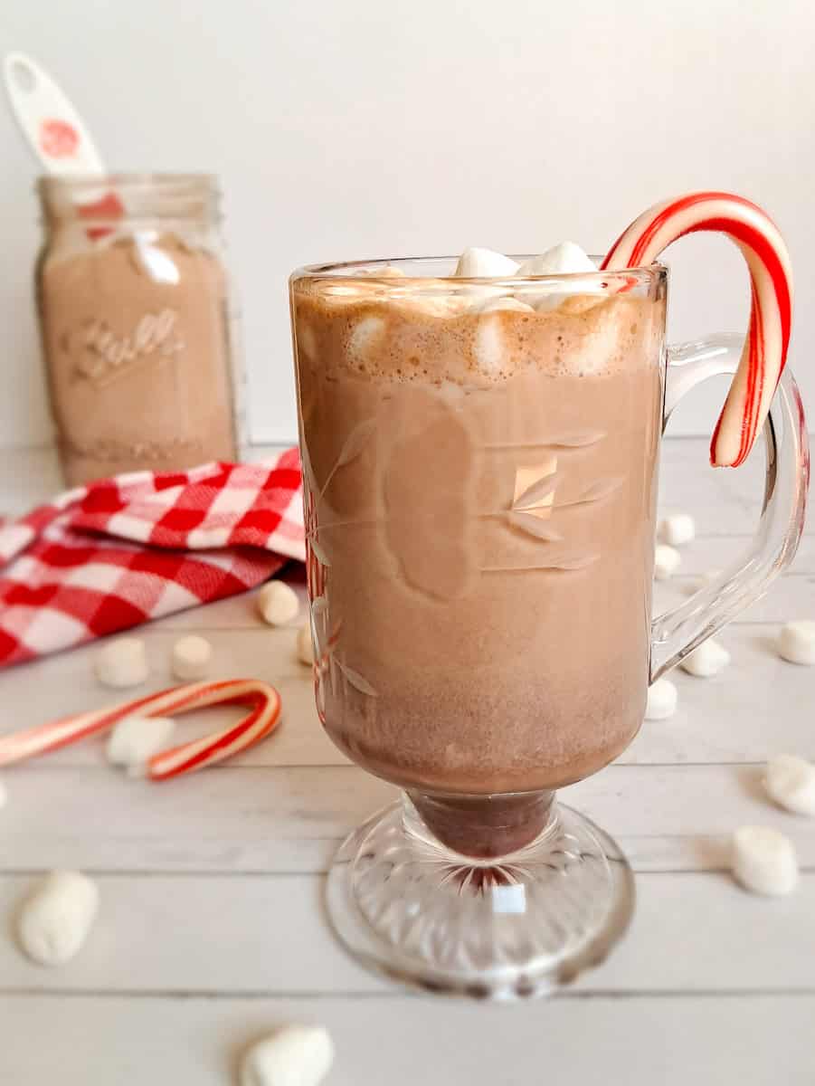 a cup of hot chocolate with a candy cane amnd marshmallows.
