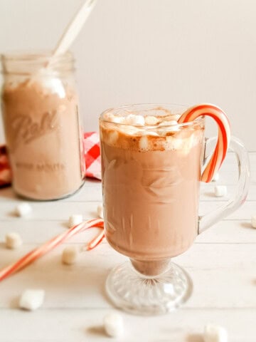 an amazing cup of hot chocolate with candy cane and marshmallows and a jar of dry chocolate. mix