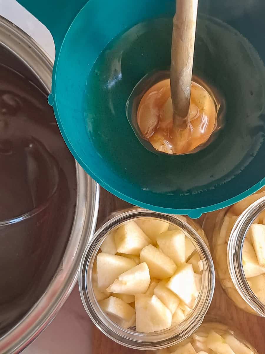 a pot of filling ready to fill the jars , pouring the filling over the apples.