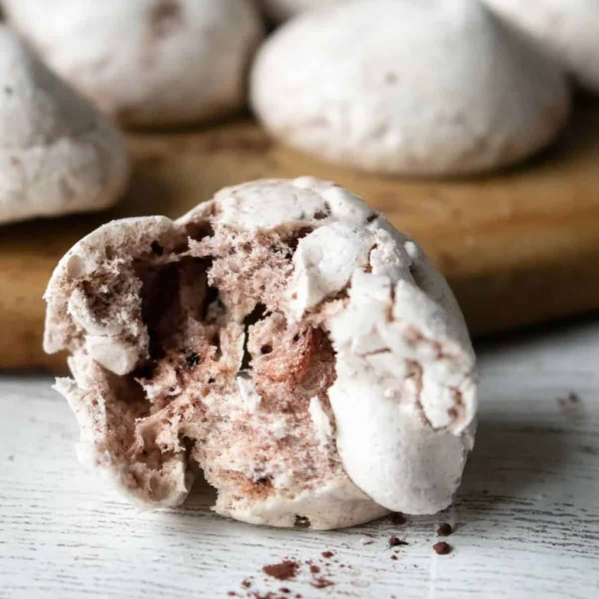 chocolate meringue cookies, one with a bite out.