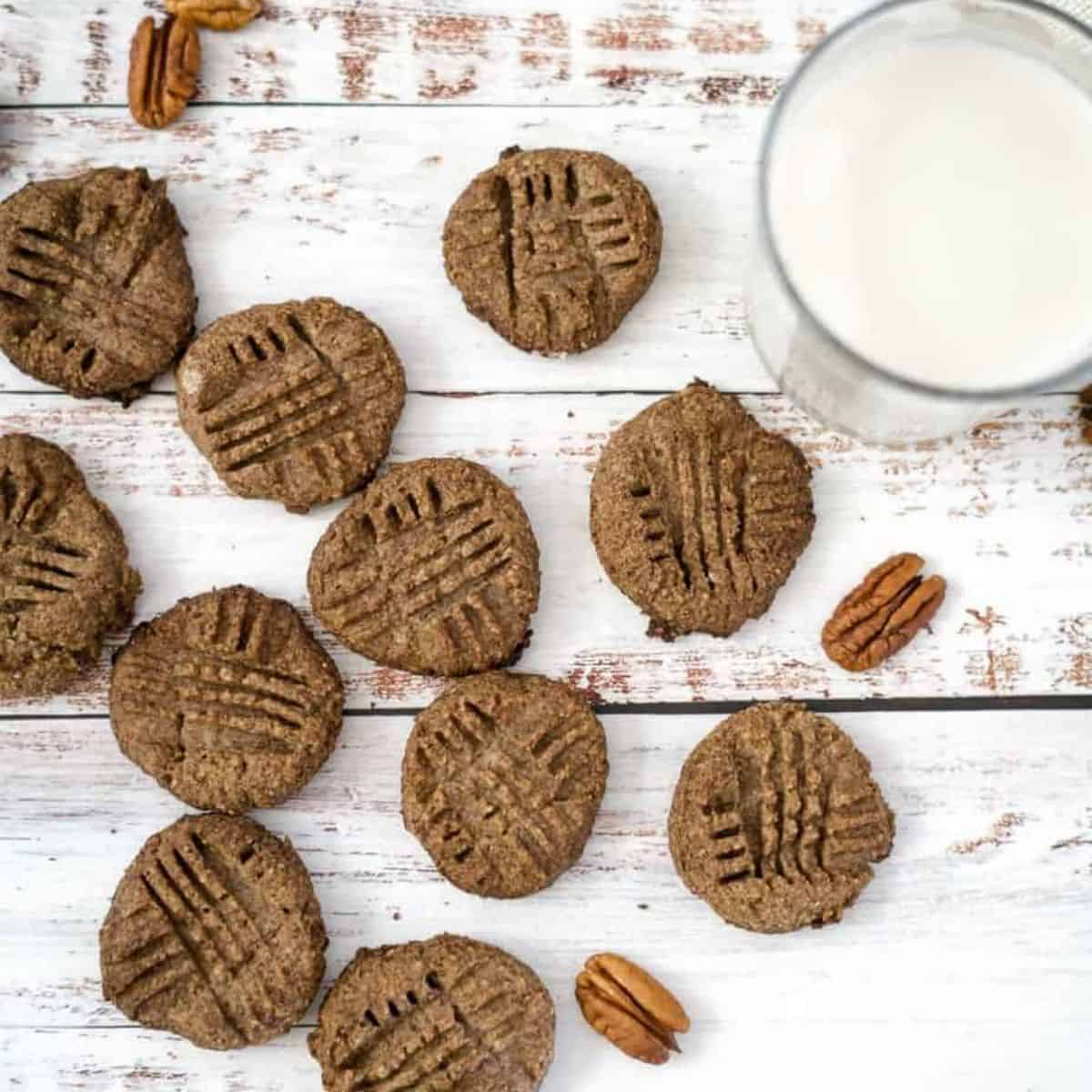 pecan butter cookies scattered around with a cup of milk.