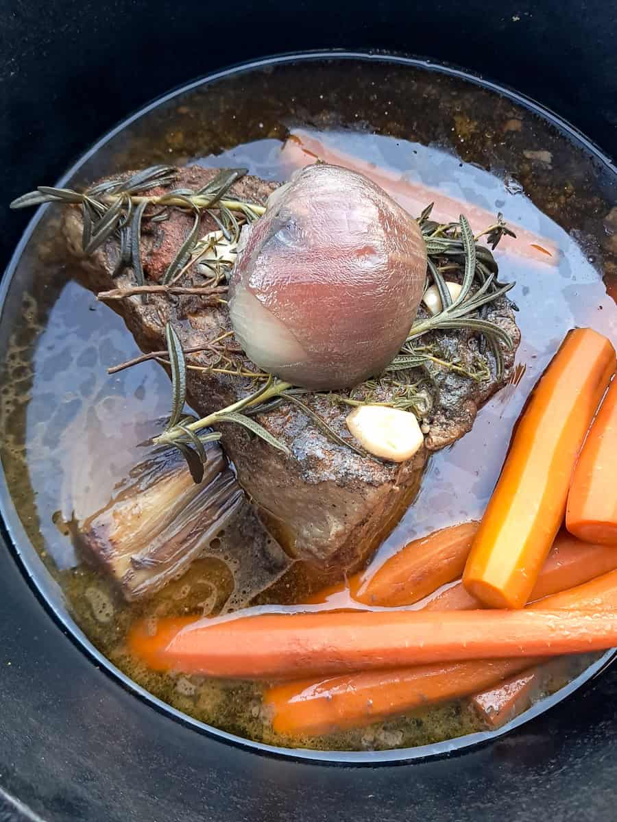cooked roast beef in a large pot with veggies.