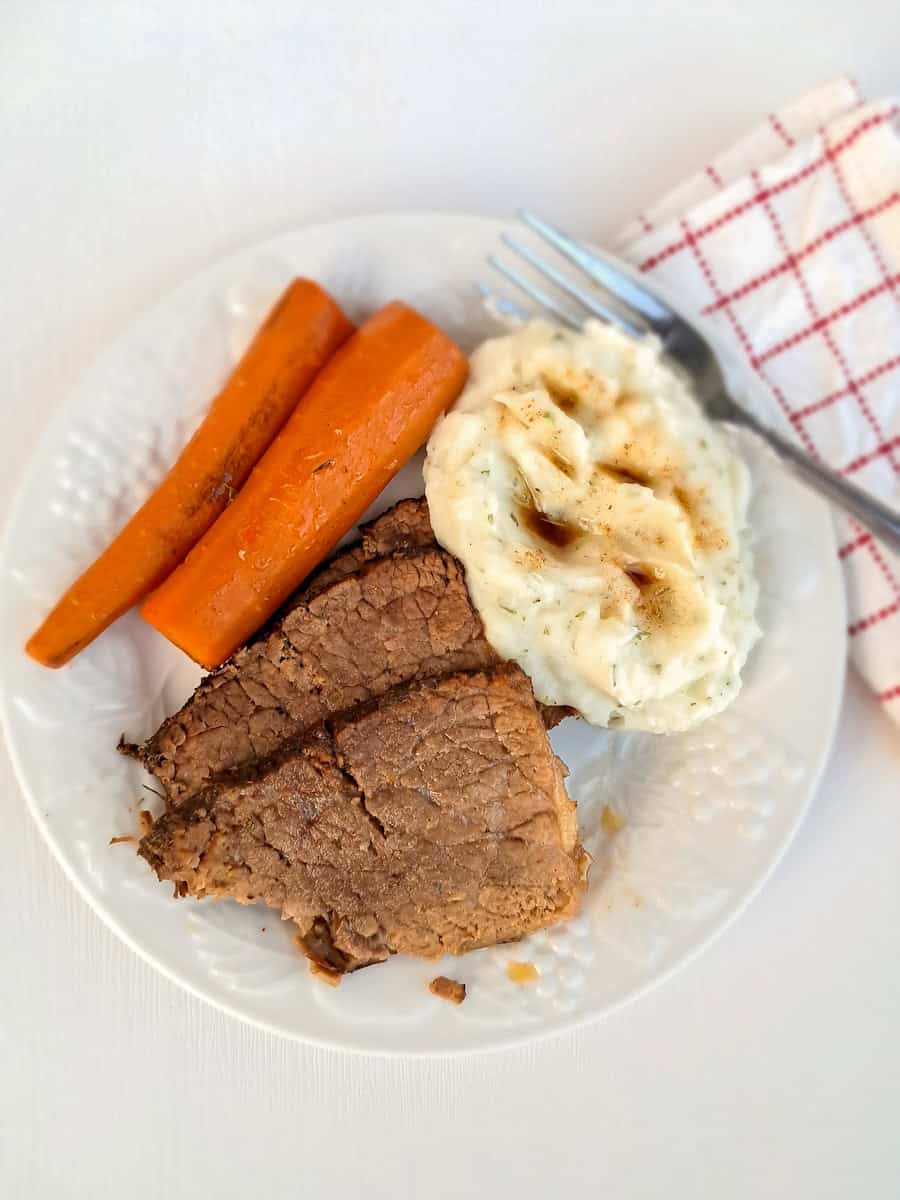 a dinner plate with mashed potatoes, roast beef, and carrots.
